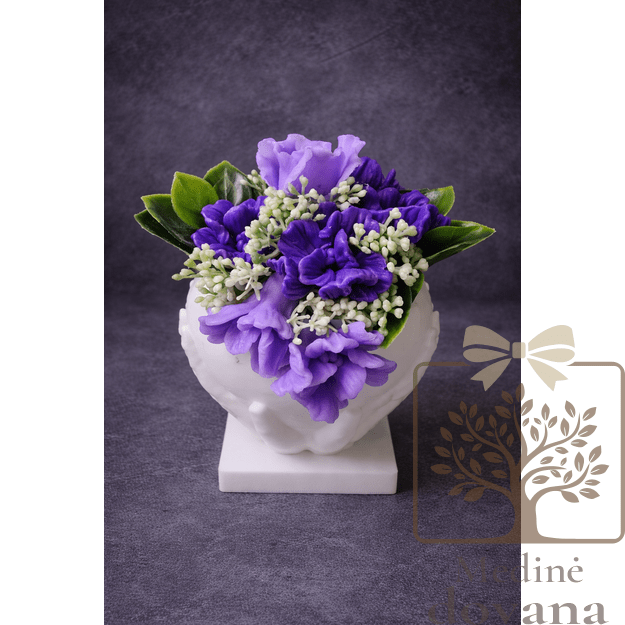 Violetinių gėlių kompozicija rankose